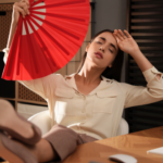 woman fanning herself with a big red fan
